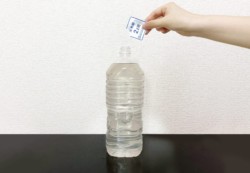 ペットボトルの水に浄水剤を入れているところ